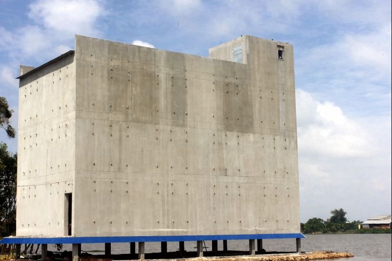 Unfinished concrete bird's nest farming building standing beside a river