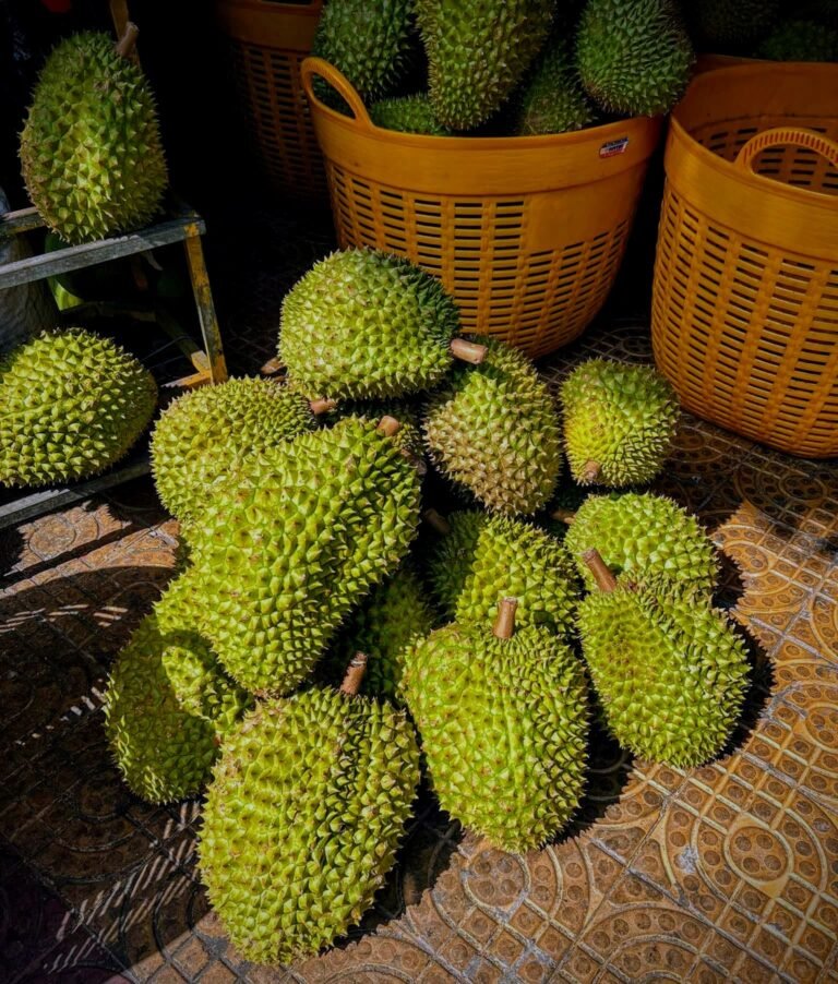 Pile of spiky durian fruit stacked beside baskets at a Vietnamese market