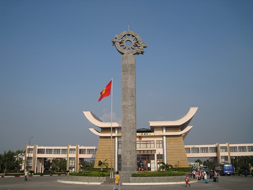 Monument with a wheel emblem and Vietnamese flag at a border checkpoint