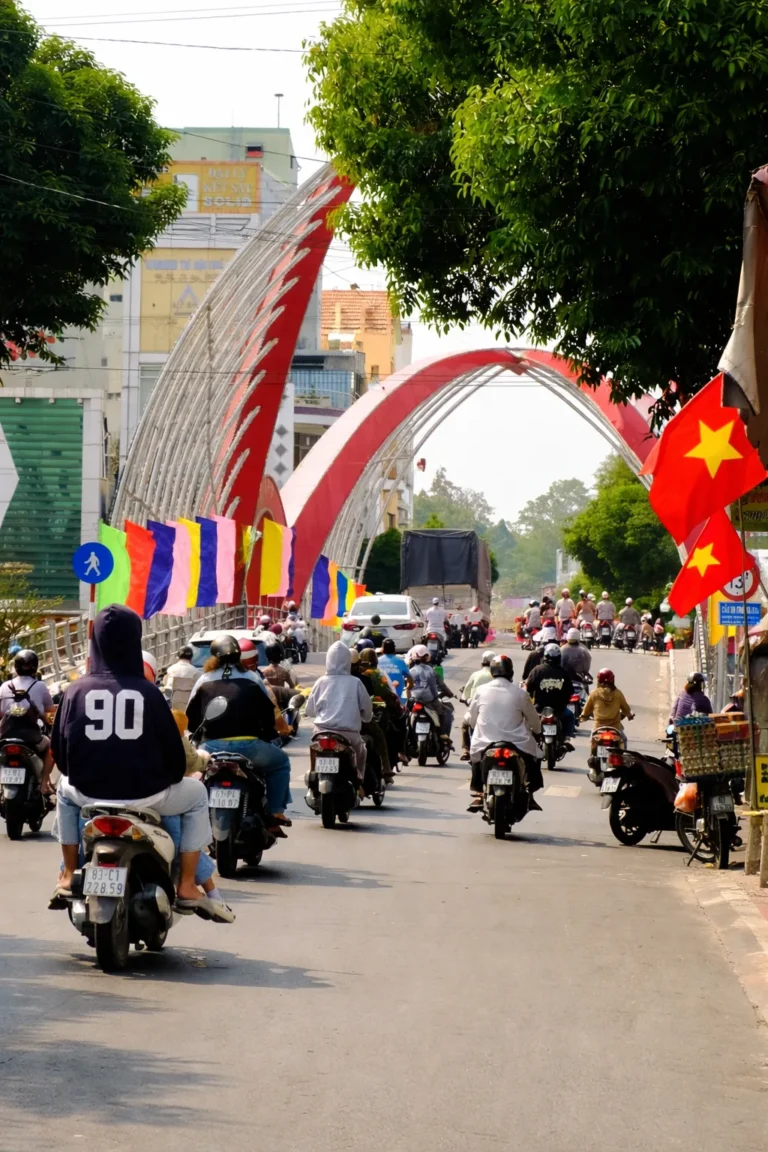 Motorbike traffic crossing a bridge decorated with Vietnamese flags in a provincial town