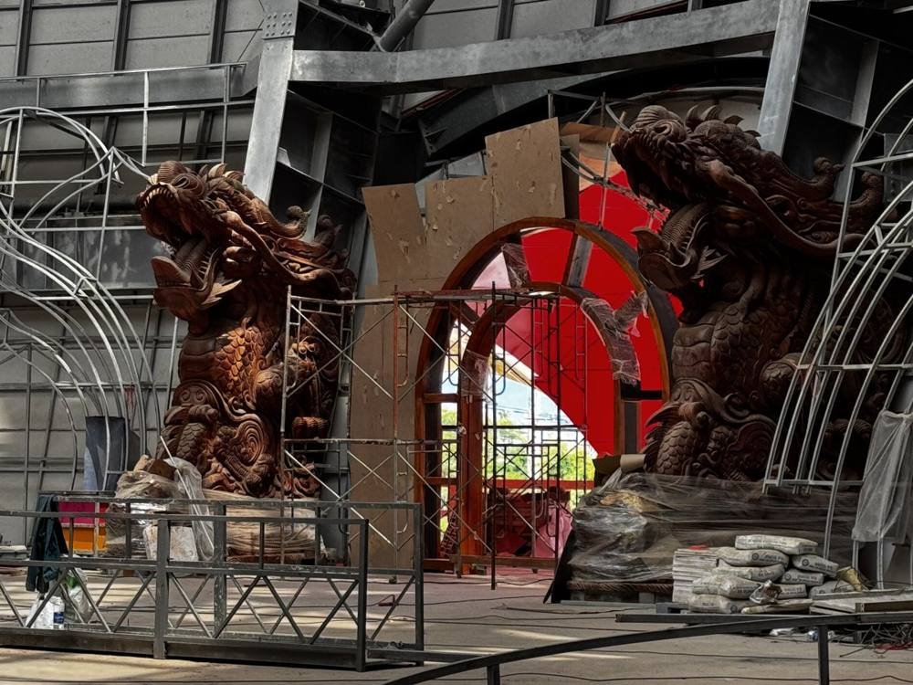 Wooden dragon statues being installed at Liên Hoa Bảo Tháp during construction, cement bags stacked nearby